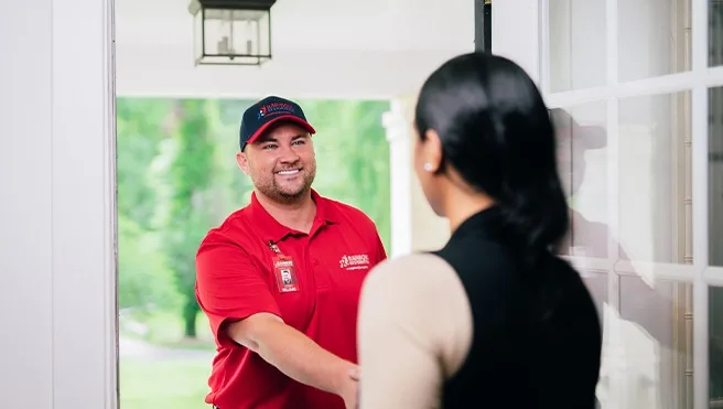 A Rainbow Restoration expert greets a Howard Beach, NY, homeowner in need of emergency restoration services at their front door. 