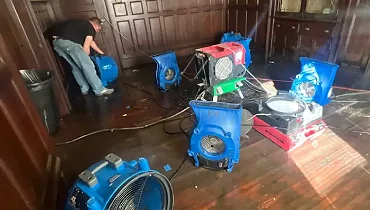 Water restoration equipment dries hardwood floors inside an older Jonesborough home after spring flooding caused indoor water damage.