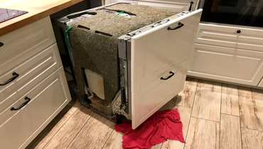 Dishwasher pulled out for inspection, repair in a residential kitchen.