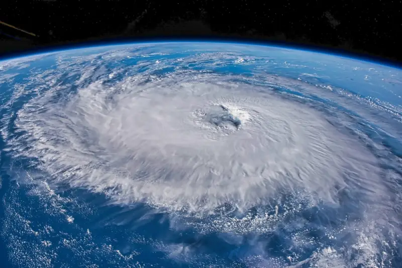 A hurricane over an ocean, seen from space with earth&rsquo;s horizon in the background.