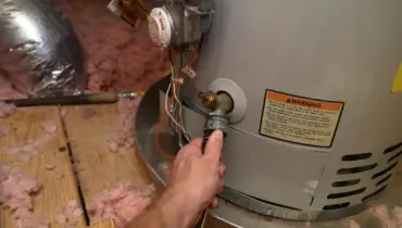 Person attaching hose to water heater to do maintenance.
