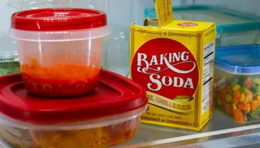 Baking soda and food in Tupperware inside a fridge.