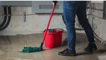 Person mops after basement flooding.